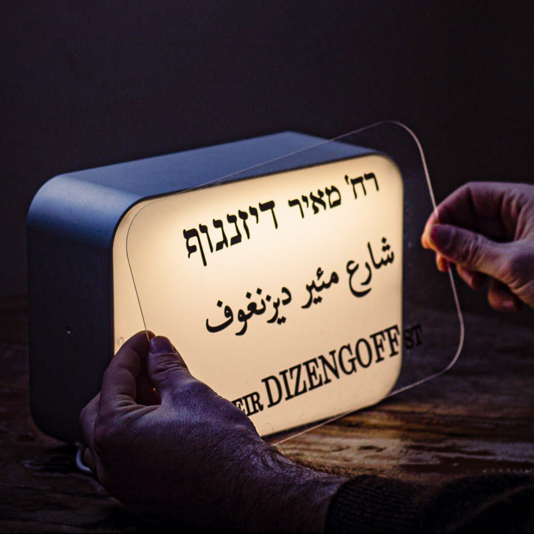 Hand holding a light-up sign with text in a dark setting